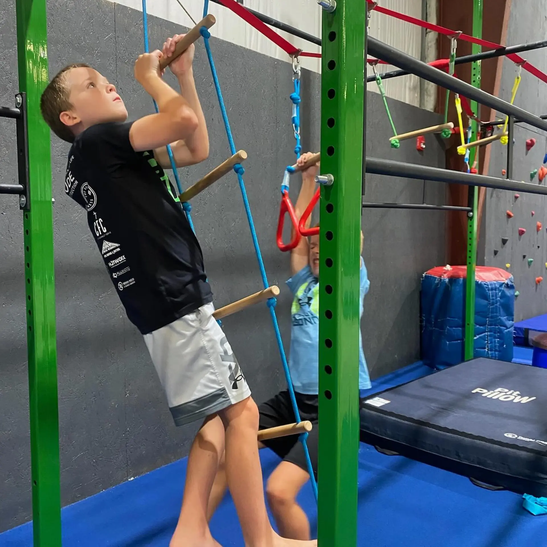 A child climbing a swinging ladder on a Ninja course.